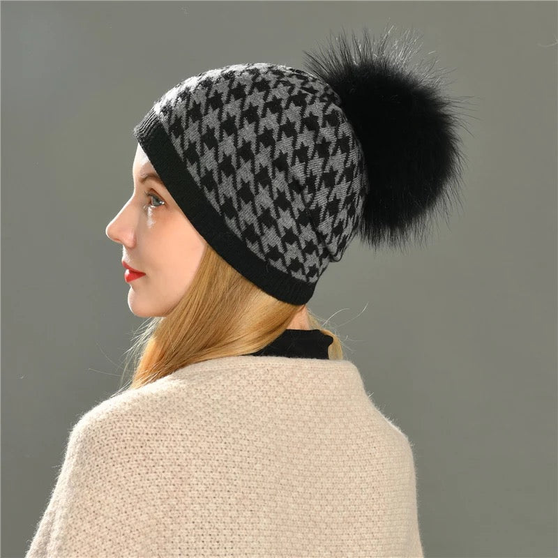A woman wearing a Hoondersthoot pom pom winter hat designed by MVFURS