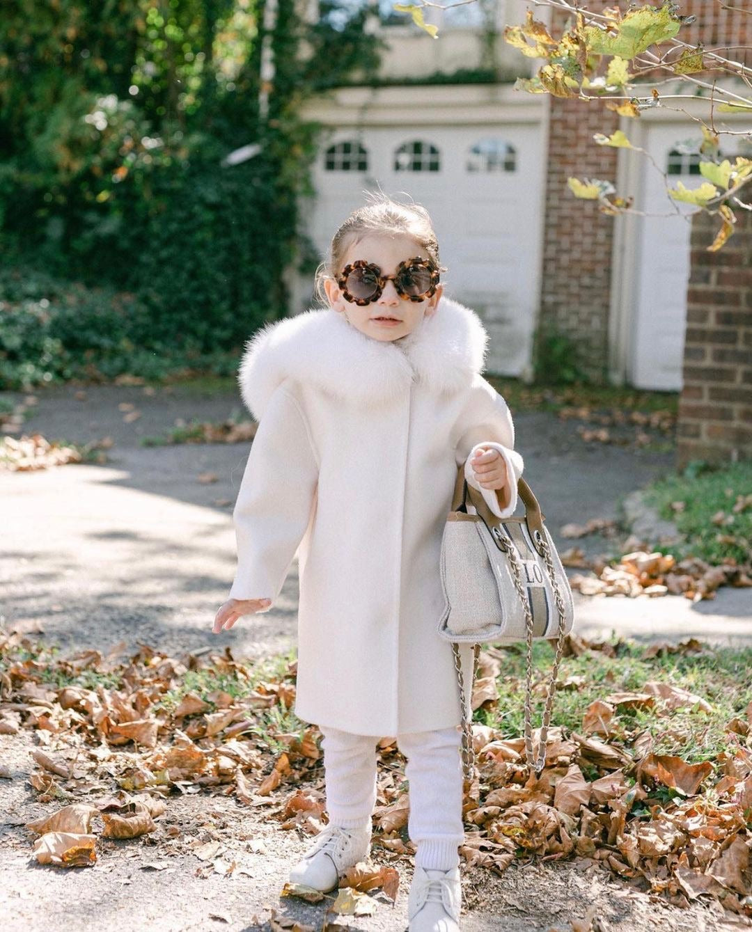A kid wearing a nude cashmere and fur coat  designed by MVFURS.