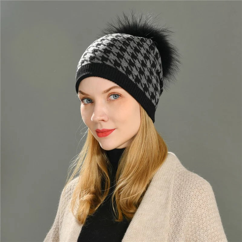 A woman wearing a Hoondersthoot pom pom winter hat designed by MVFURS