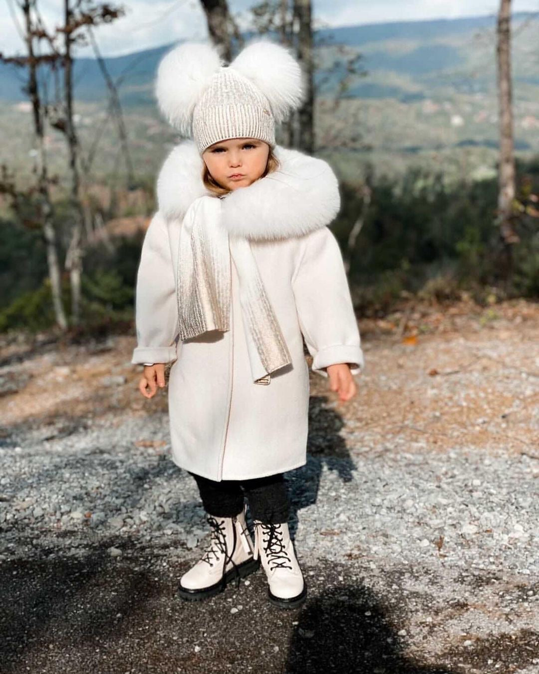 A kid wearing a nude cashmere and fur coat designed by MVFURS.