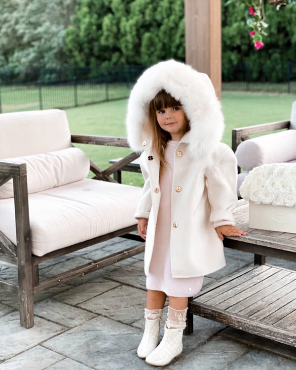 A kid wearing a nude cashmere and fur coat  designed by MVFURS. 