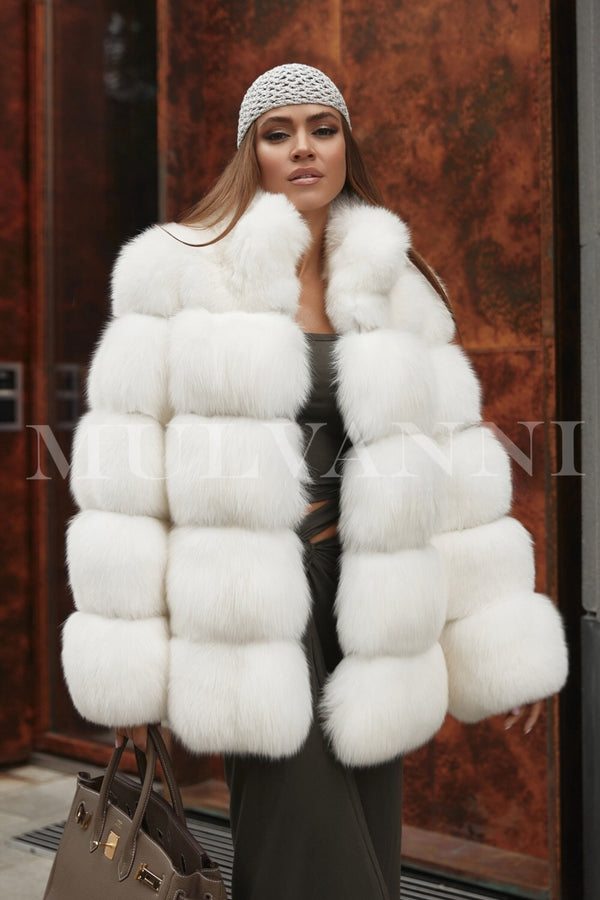 A woman wearing an elegant and luxurious white fox fur coat, featuring a soft, plush texture and a flowing silhouette. The coat exudes sophistication and warmth, making it a stunning choice for formal winter occasions.