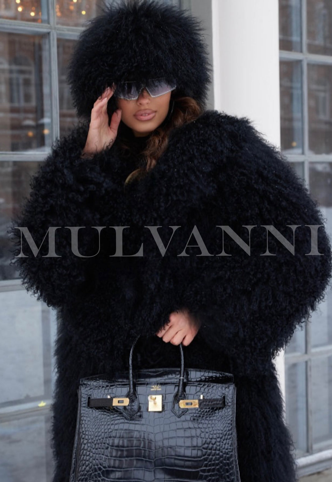 A woman in a luxurious long black Mongolian coat, highlighting its exquisite craftsmanship and paired with a coordinating Mongolian hat. The ensemble offers both style and comfort for winter occasions.