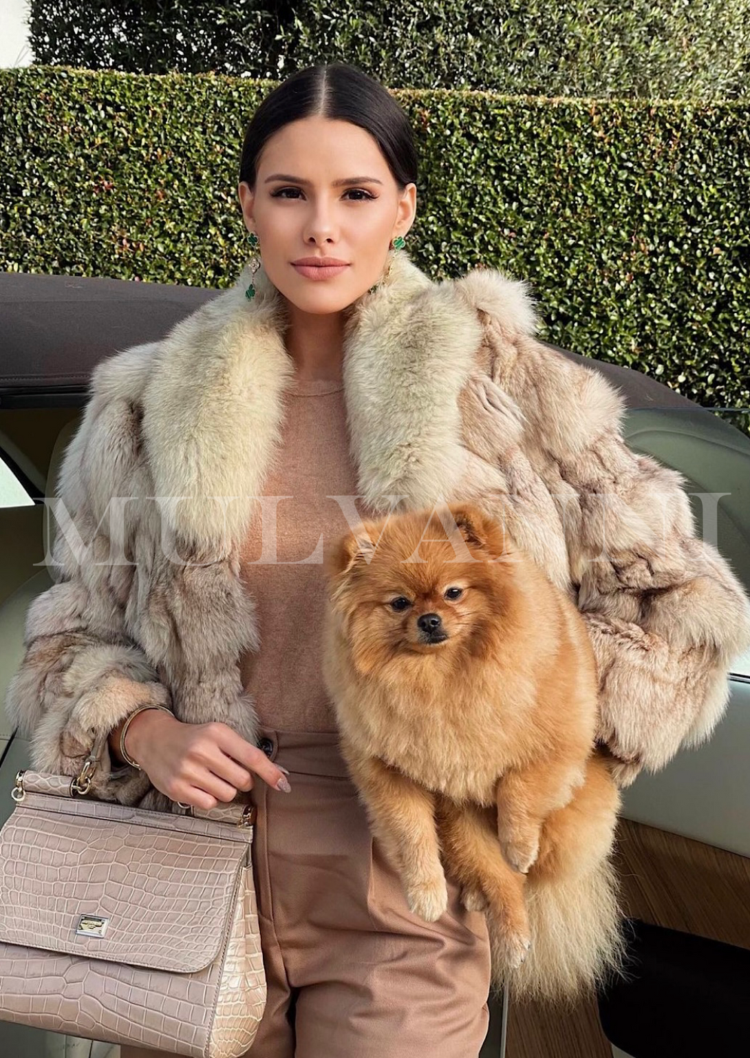 A woman showcasing a textured fox fur coat in a warm beige hue, highlighted by a large, plush collar. The coat’s unique design and soft fur make it a statement piece for winter.