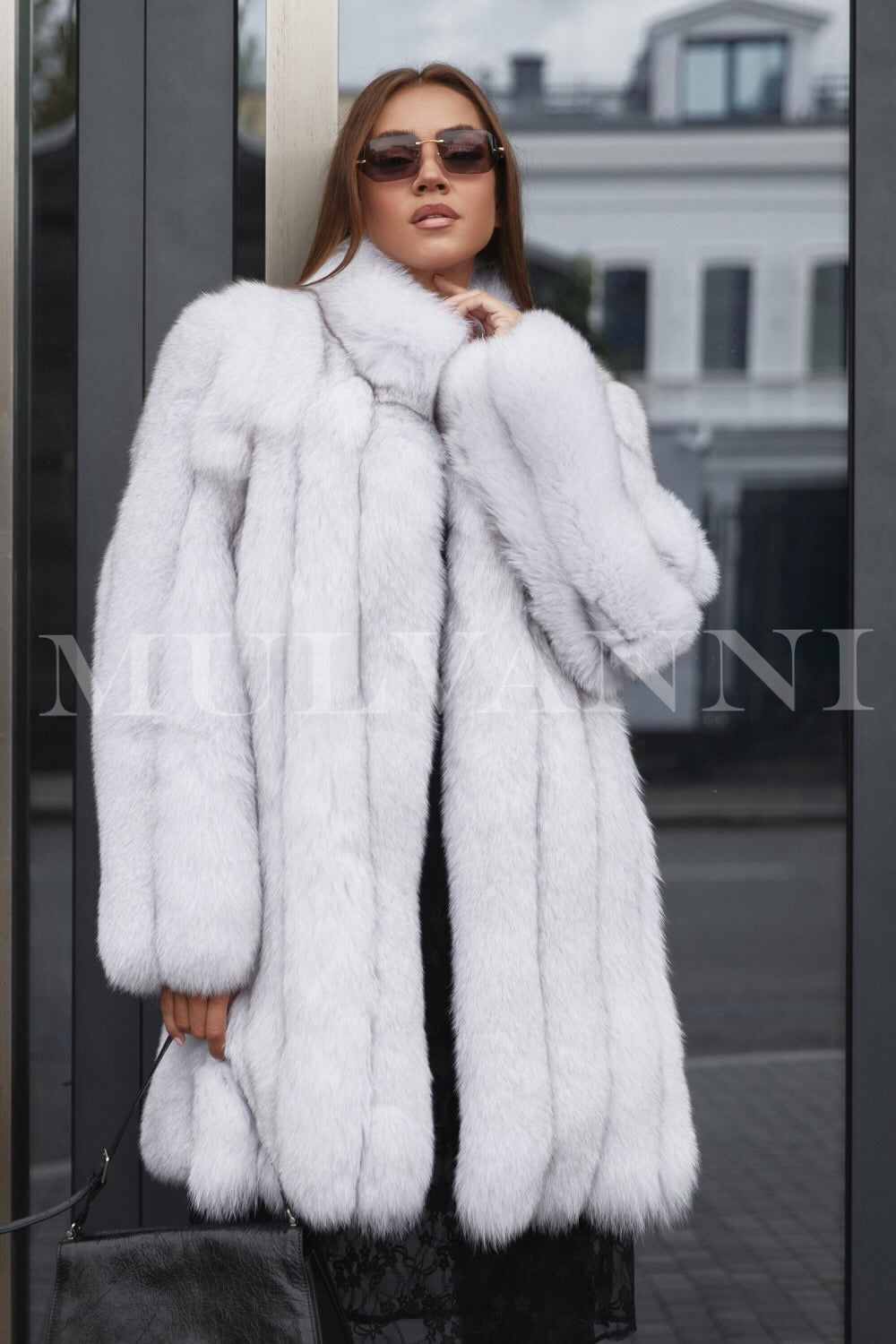 A woman wearing a midi white fox fur coat that showcases its luxurious quality, paired with stylish sunglasses. The coat features a soft, plush texture and a flowing silhouette, exuding elegance and sophistication for winter outings.