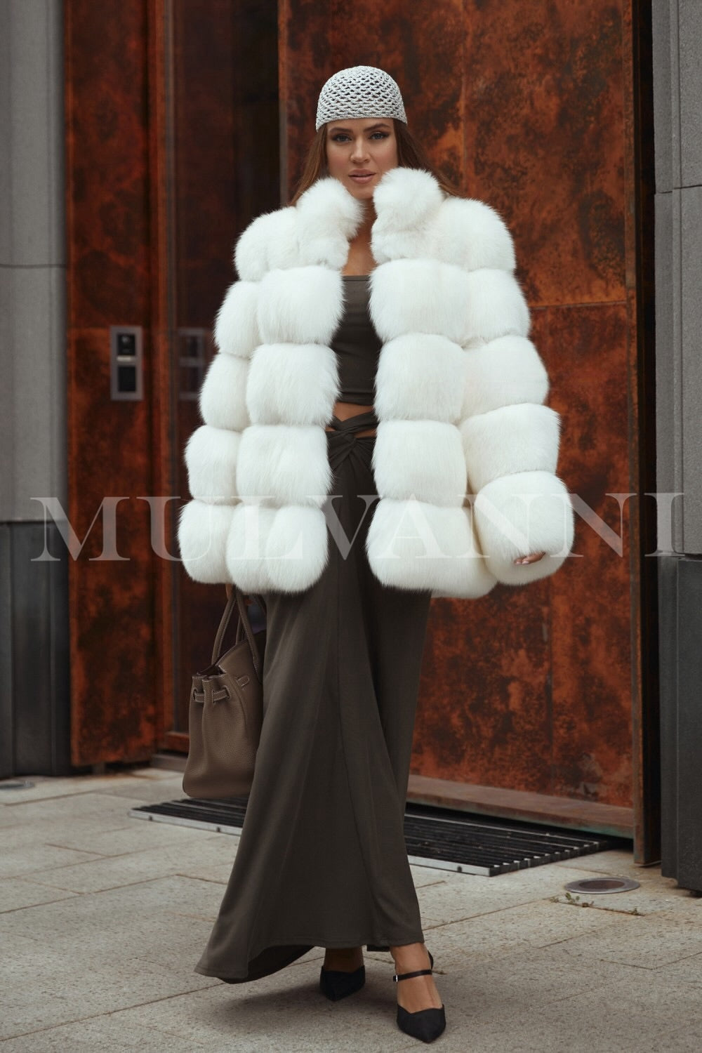 A woman in a luxurious white fox fur coat that highlights its exquisite softness and elegant design. The coat features a flattering fit and a timeless style, providing both warmth and sophistication for cold-weather events.