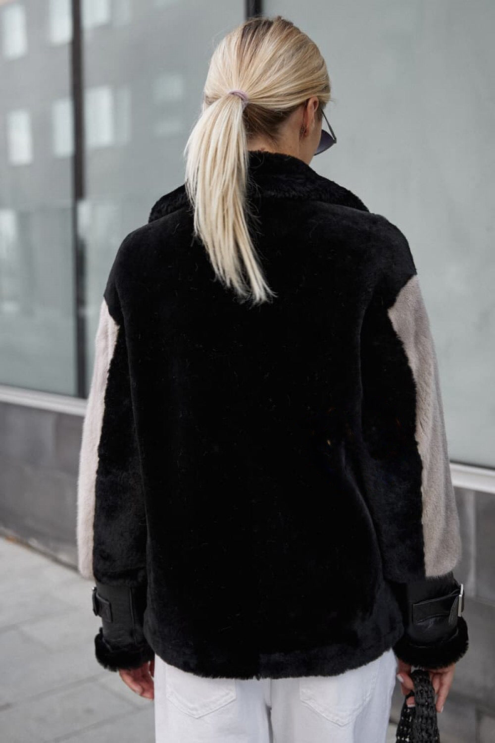 A woman in a stylish leather jacket adorned with plush grey mink fur, showcasing a blend of modern and luxurious elements. The jacket’s design provides warmth and sophistication for winter outings.