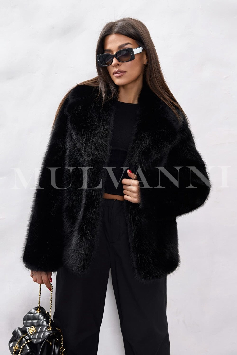 A woman dressed in a cozy black faux fur coat, showcasing its soft texture, complemented by fashionable sunglasses. The coat's elegant silhouette adds sophistication to her winter style.