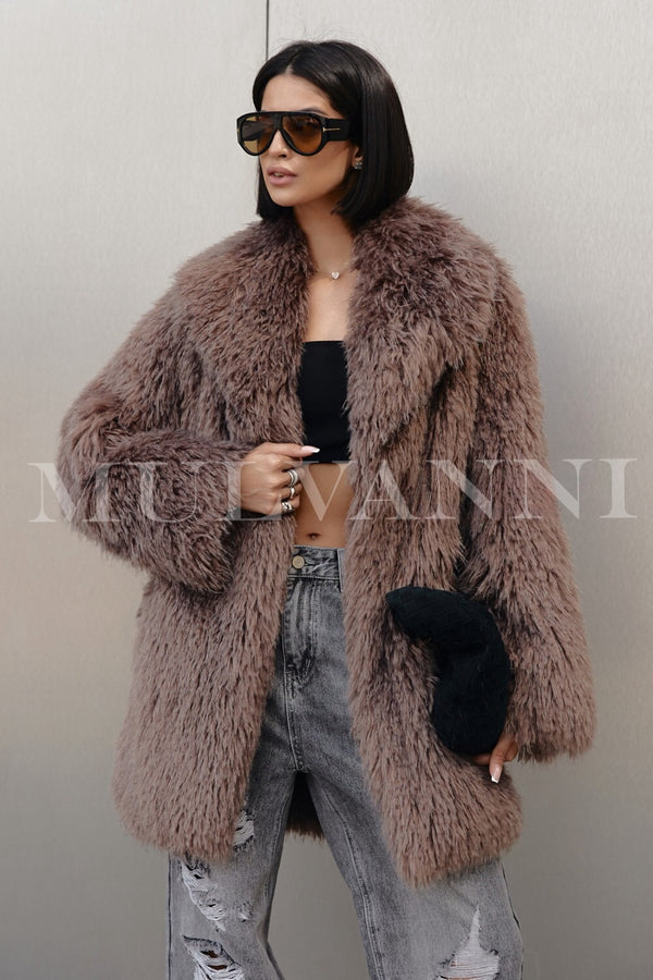 A woman wearing a brown faux Mongolian coat, characterized by its rich, textured appearance, paired with stylish sunglasses. The coat's luxurious design and flowing silhouette create a chic and fashionable look for winter.