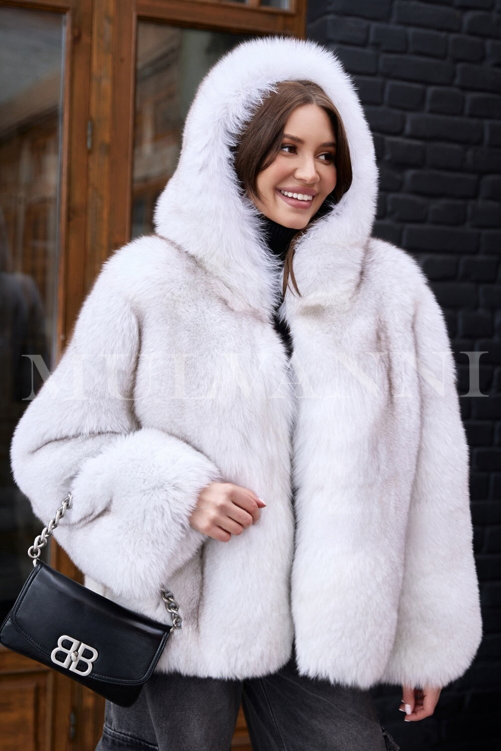 A woman dressed in a luxurious hooded plush white fox fur coat, showcasing its high-quality softness and warmth. The coat's elegant design and cozy hood provide both style and comfort for winter's chill.