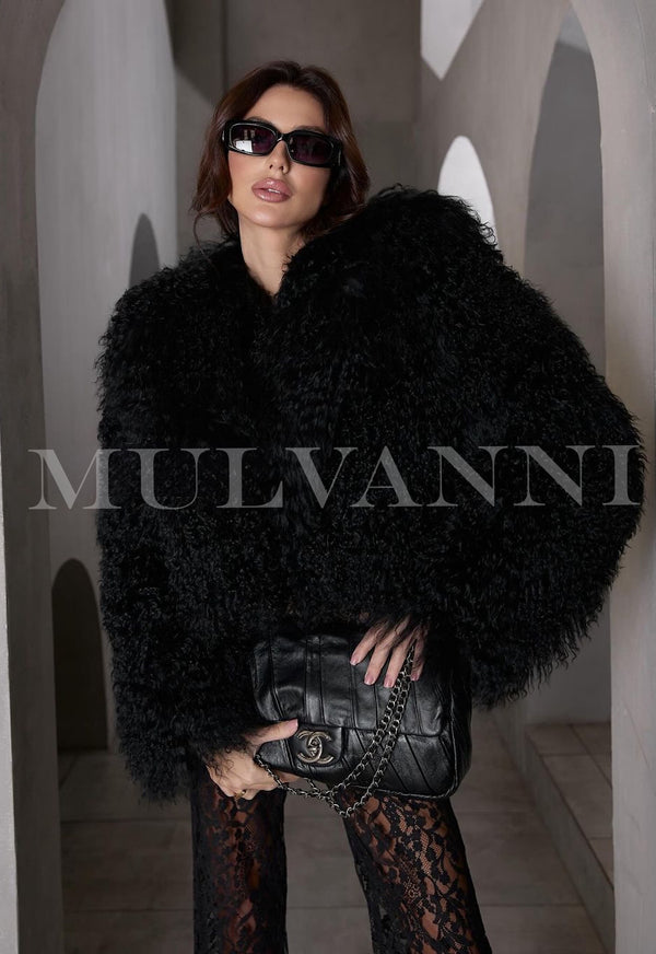 Woman wearing EVELYN Black Mongolian Coat and sunglasses, holding a black leather bag, exuding trendy and luxurious style