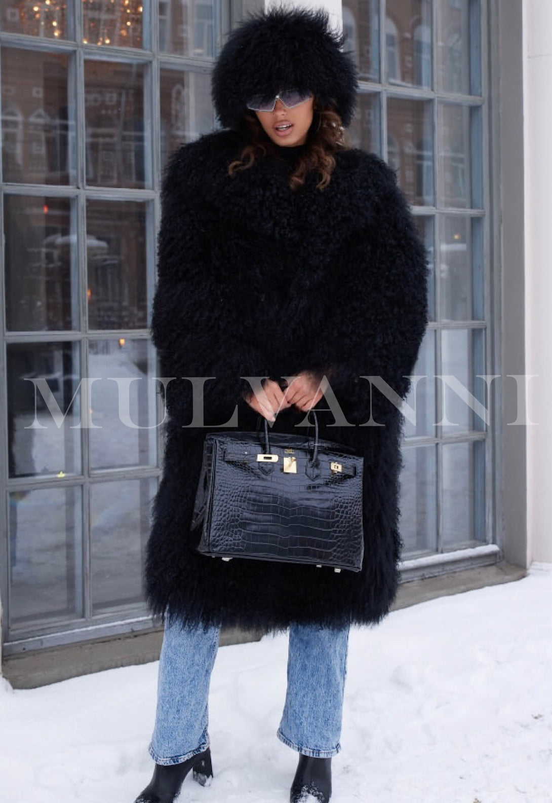 A woman wearing a long black Mongolian coat, showcasing exceptional quality and luxurious texture, paired with a matching Mongolian hat. The ensemble exudes elegance and warmth, making it a stylish choice for winter.