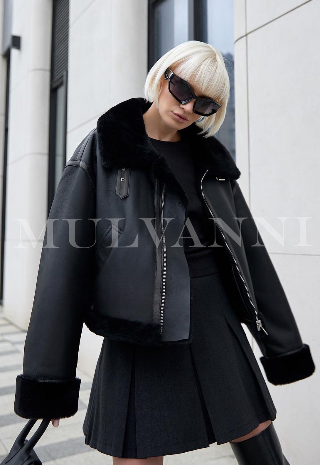 A woman dressed in a premium black shearling coat, complemented by trendy sunglasses. The coat's rich texture and tailored fit highlight its high quality, creating a fashionable and refined winter ensemble.