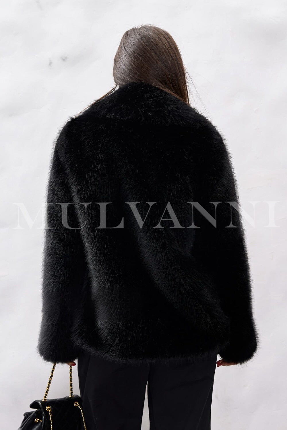 A woman in a luxurious black faux fur coat that highlights its plush softness, paired with sleek sunglasses. The combination creates a trendy and chic ensemble perfect for cold-weather outings.