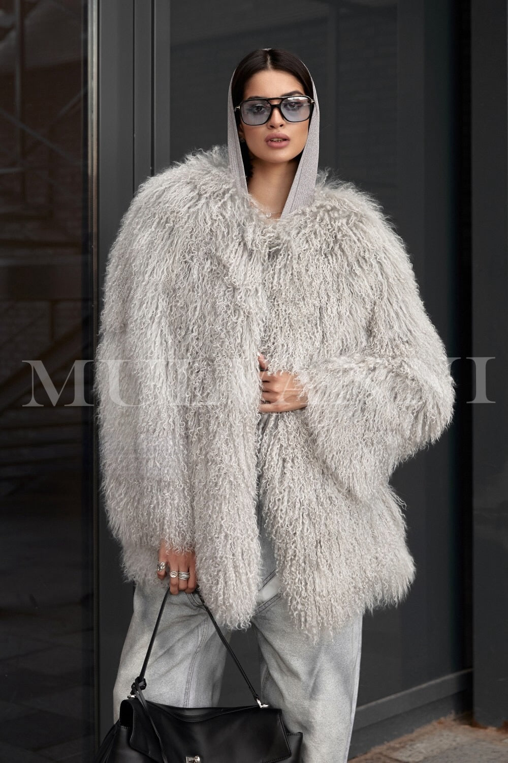 A woman wearing a fashionable grey Mongolian coat, featuring a soft, textured exterior and a contemporary design. The coat's stylish silhouette and warm fabric make it an ideal choice for chic winter outfits.