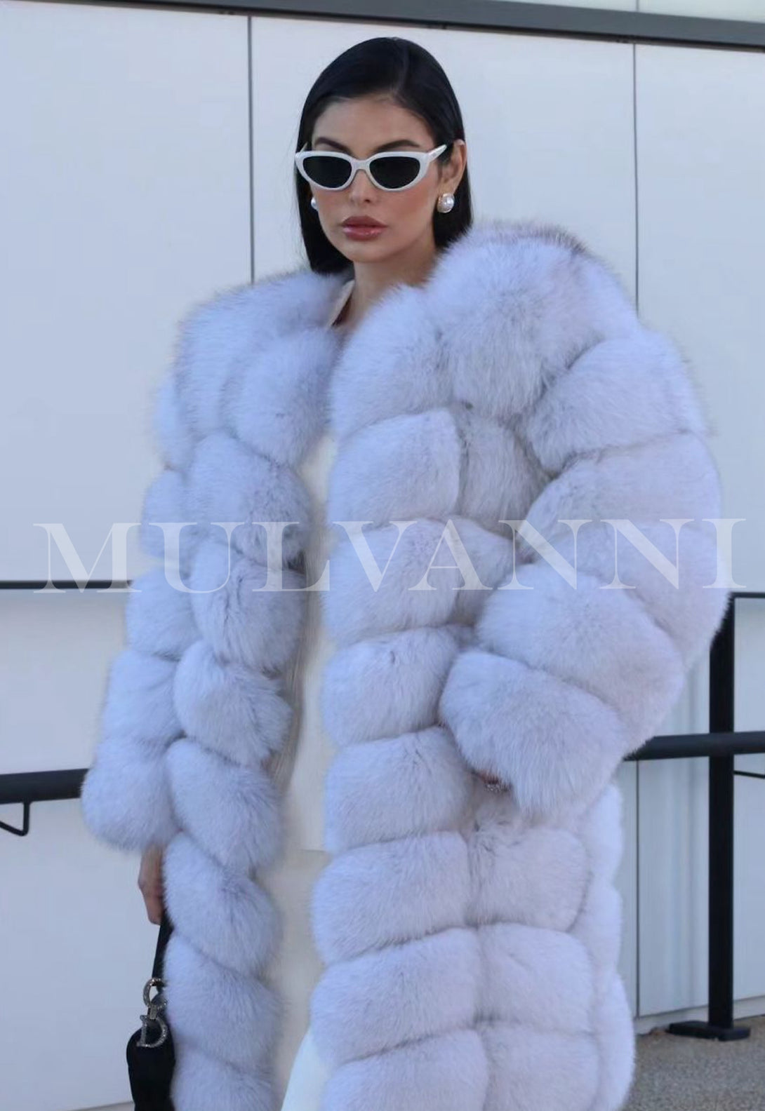 A woman in a stylish midi-length white fox fur coat, highlighting its rich, soft fur.