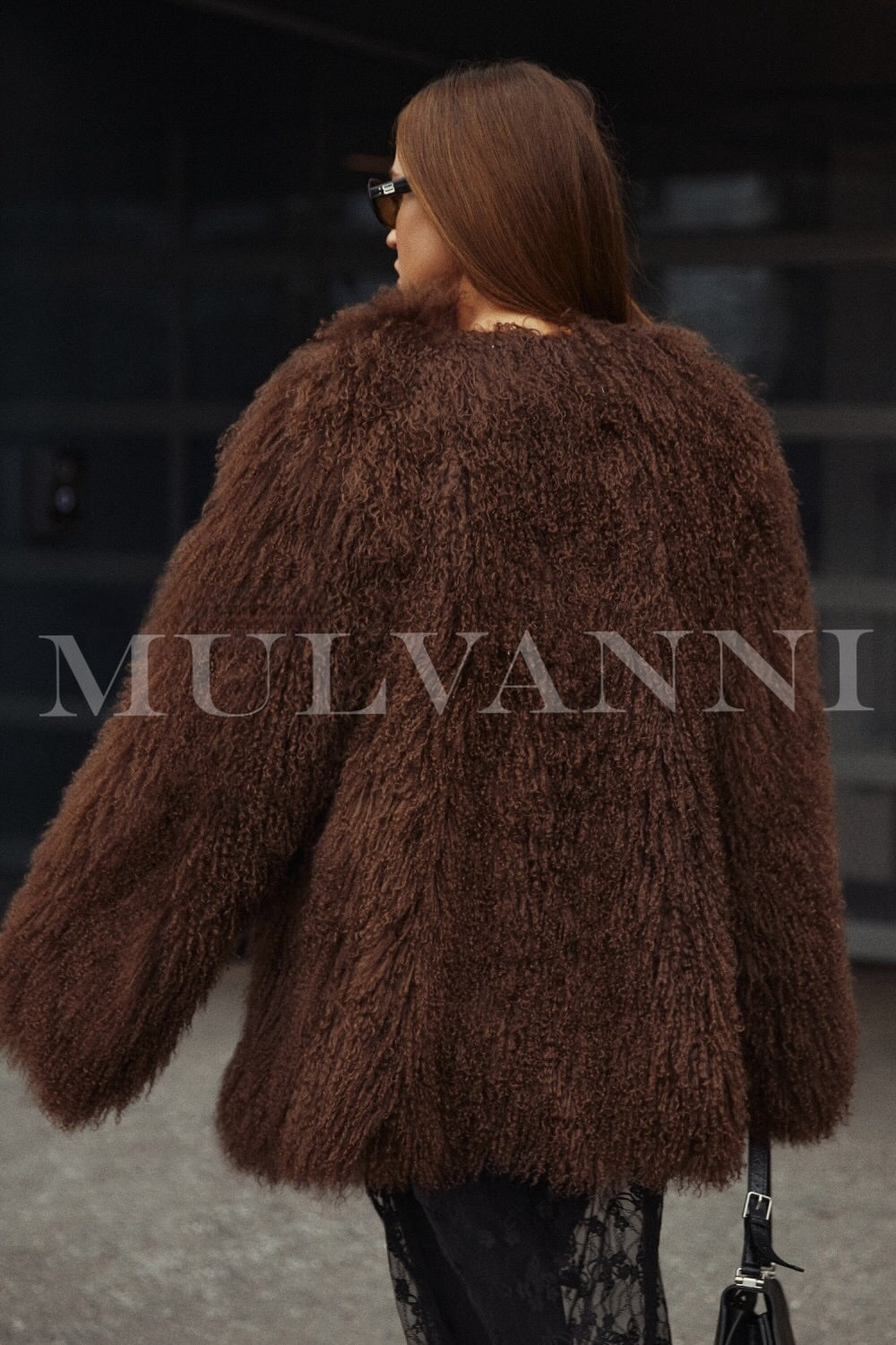 A woman dressed in a premium brown Mongolian coat that showcases its exceptional quality and rich, plush fur. 