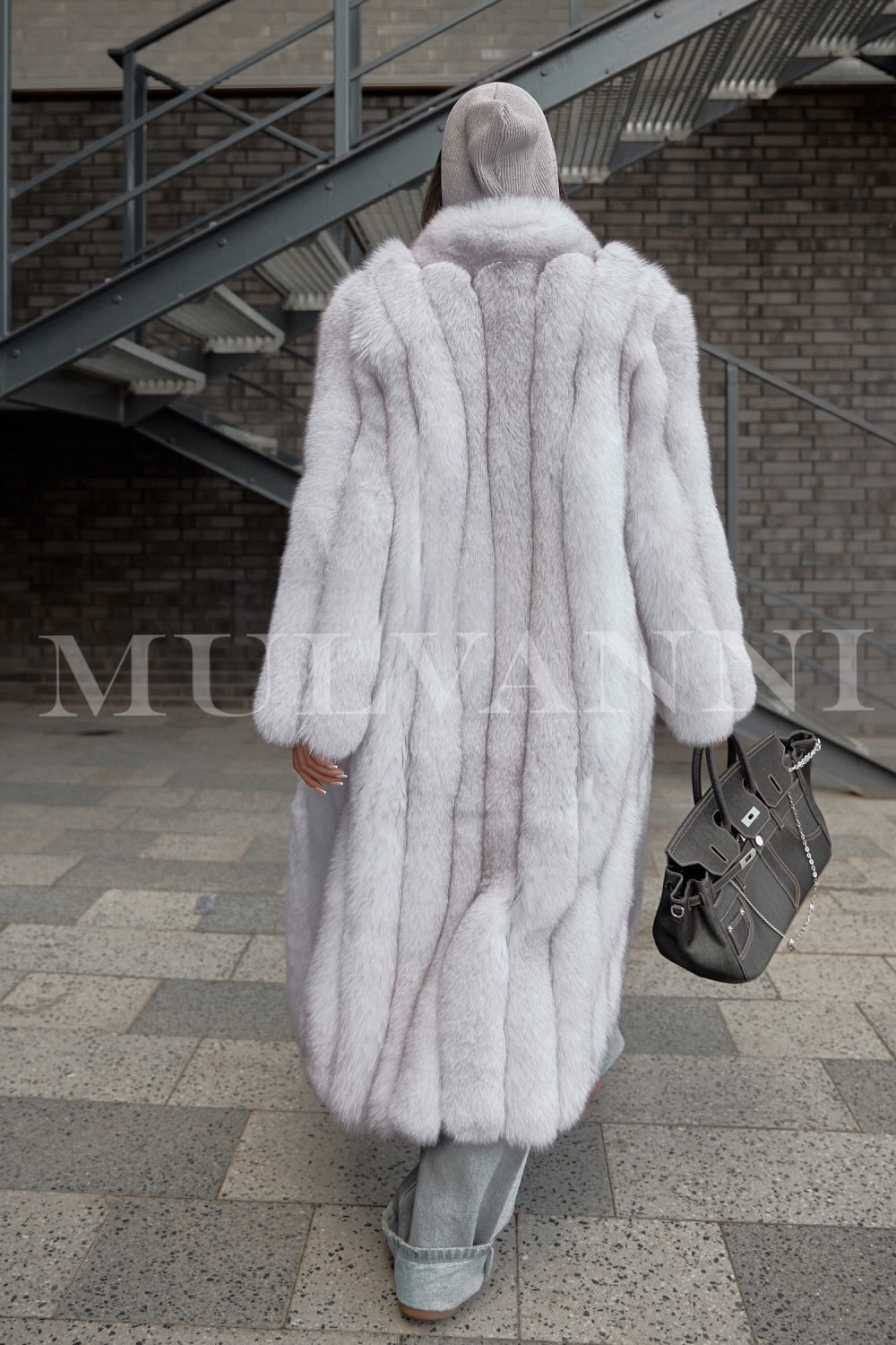 A woman wearing an exquisite long white fox fur coat, epitomizing high fashion with its rich texture and flowing lines. The coat not only provides warmth but also elevates her winter style to a sophisticated level.