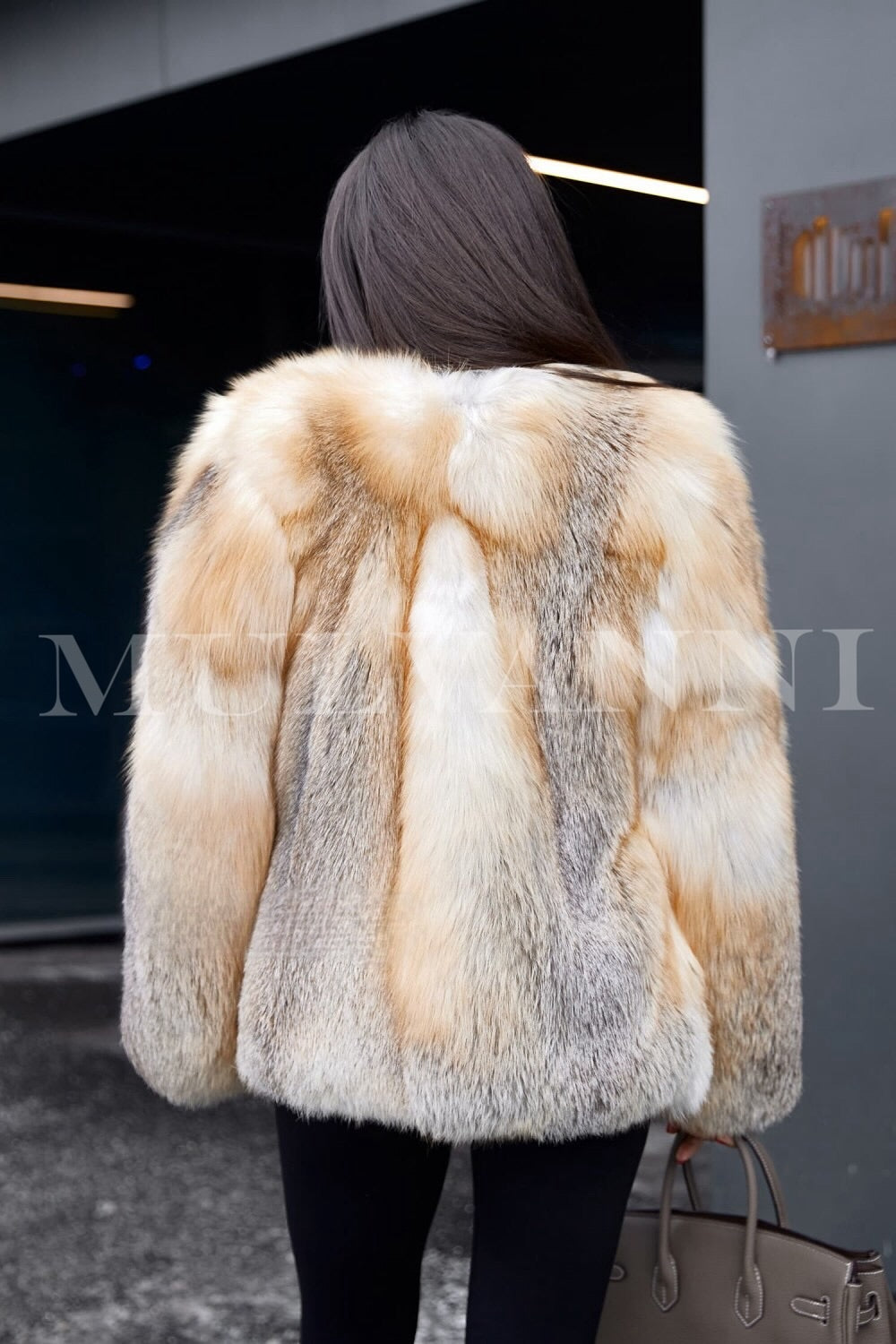 A woman wearing a short, opulent gold crossed fox fur coat, featuring a soft, voluminous design. The coat's warm golden hue and tailored fit provide both luxury and warmth, ideal for making a statement in cold weather.