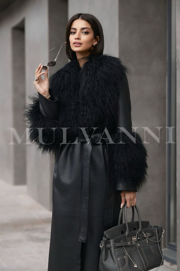 A woman wearing a black leather trench coat adorned with Mongolian fur at the collar and cuffs. The coat features a sleek design and fitted silhouette, combining luxury and style for a chic winter look.