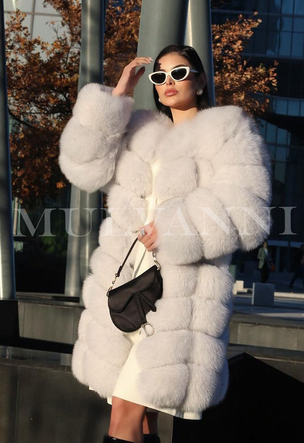 A woman wearing a luxurious white fox fur coat of midi length. The coat features a soft, plush texture and a chic silhouette, offering warmth and sophistication for a stylish winter look.