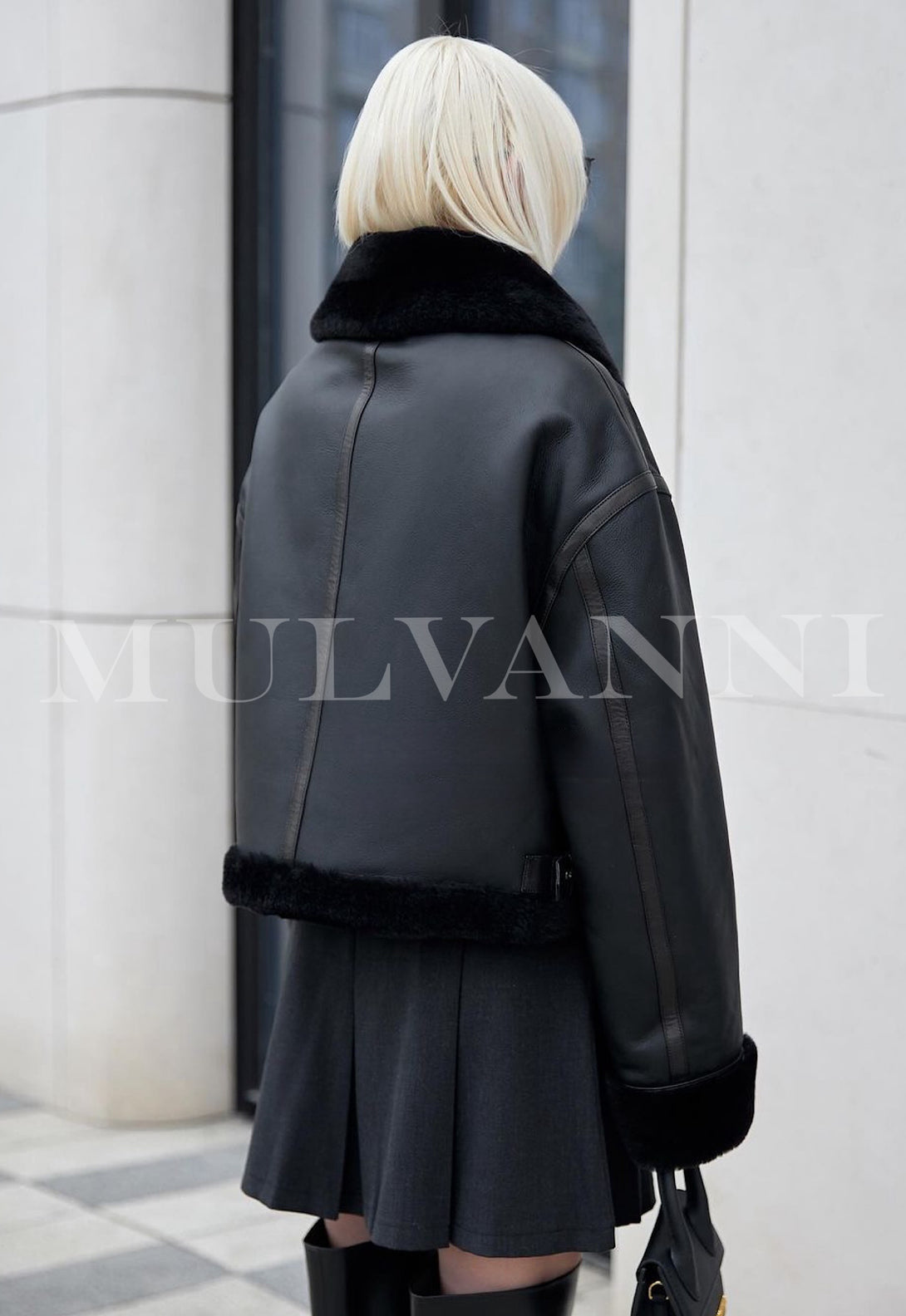 A woman in a luxurious black shearling coat paired with sleek sunglasses. The coat's high-quality material and modern silhouette provide both warmth and an effortlessly stylish look.