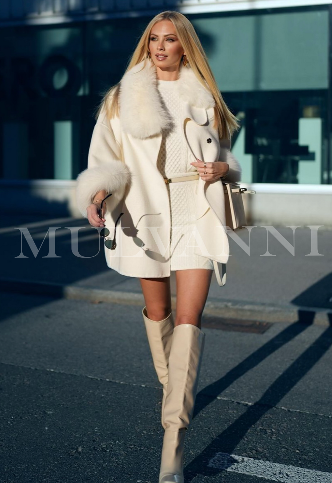 Woman wearing ANETTE Off White Oversized Cashmere Coat with Fox Fur walking outdoors, showcasing elegant winter fashion style.