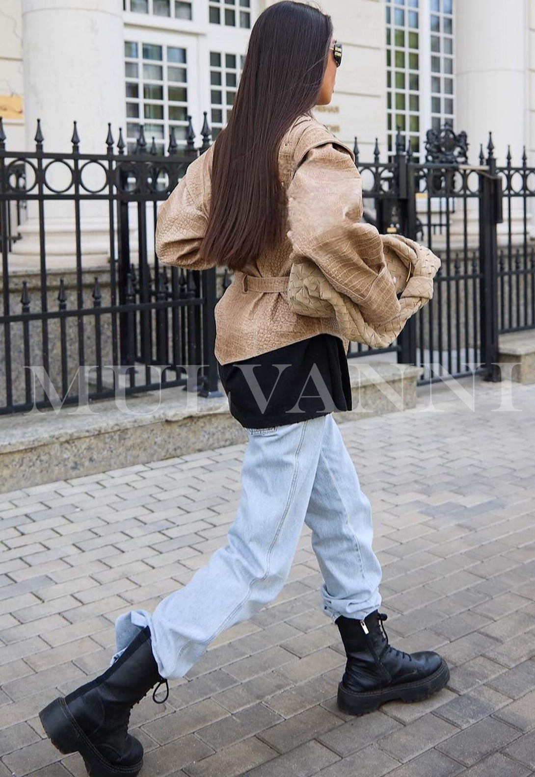 Woman wearing JAKI Embossed Croc Leather Jacket with tailored fit, walking confidently in the city.