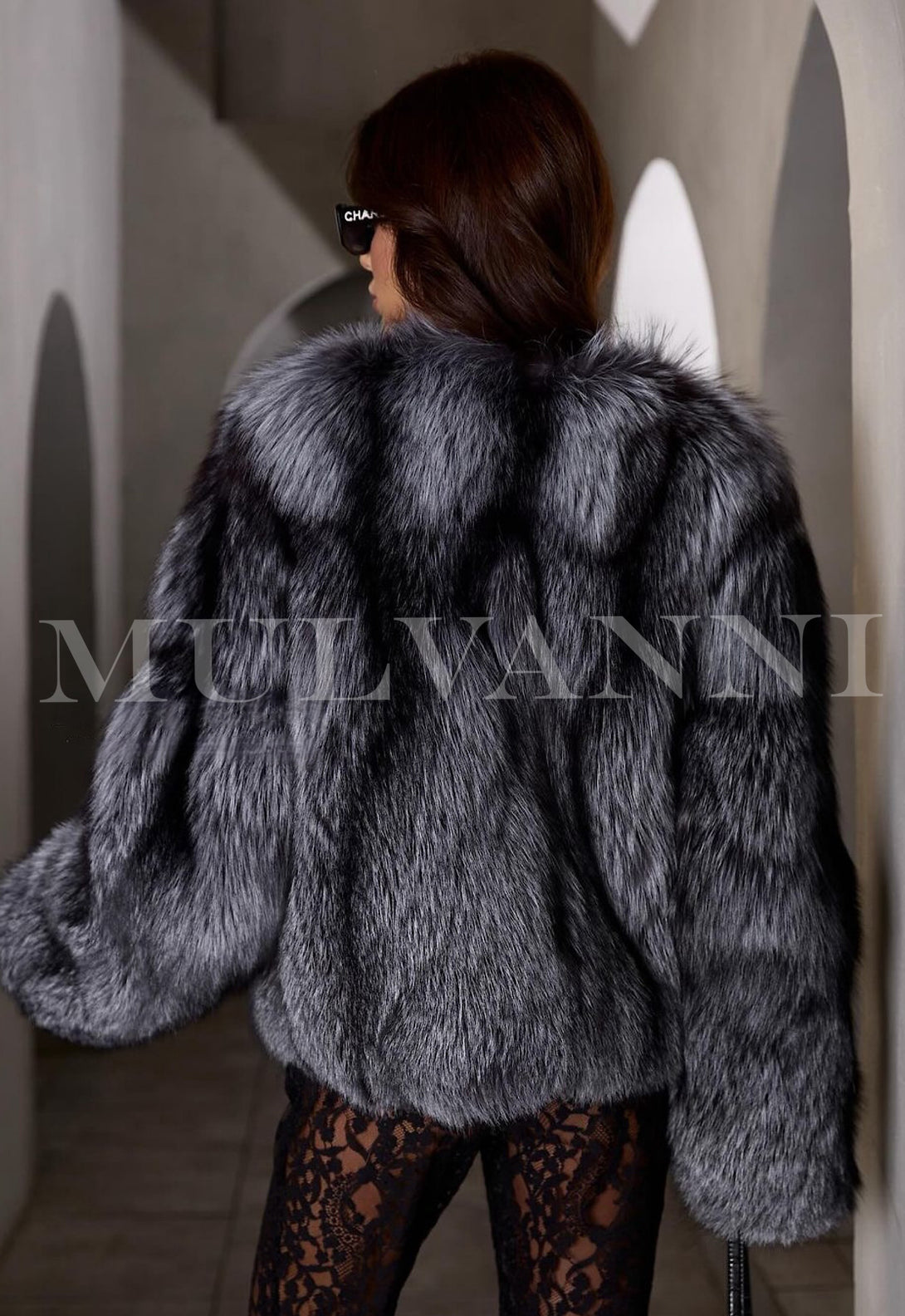 This elegant silver fox fur coat enhances the woman's look, featuring a soft, lustrous finish that complements her overall attire.