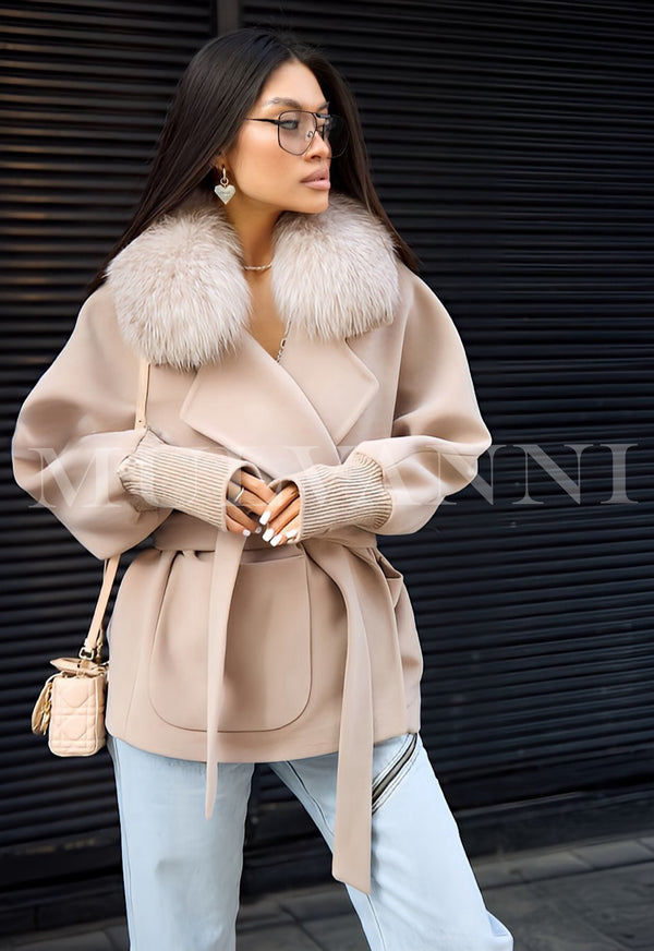 Woman wearing beige cashmere coat with detachable fox fur collar and matching belt, styled casually with light-wash jeans.