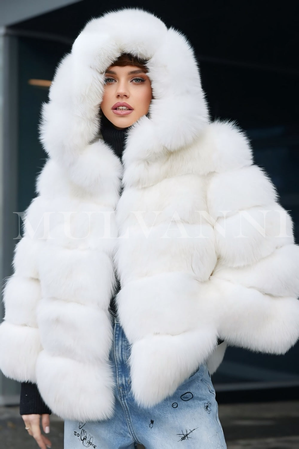 A woman wearing a soft white faux fur coat with black accents and a cozy hood. The coat's plush texture and stylish design provide warmth and elegance, making it a chic choice for winter.