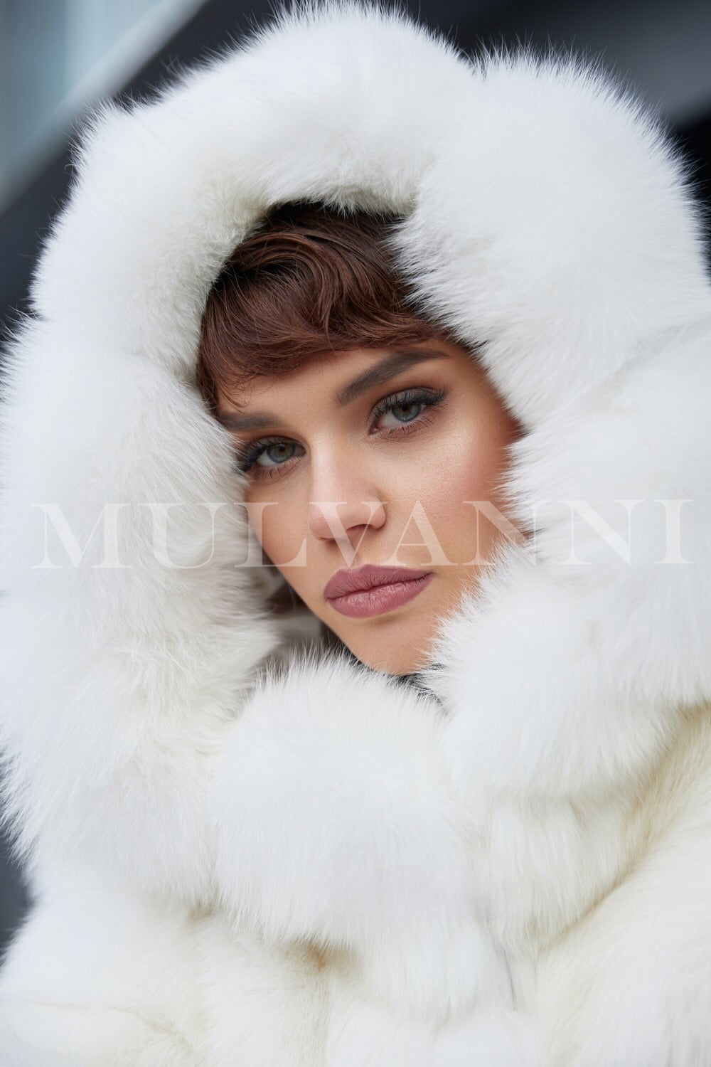 A woman wearing a beautifully soft white faux fur coat with a stylish hood. 