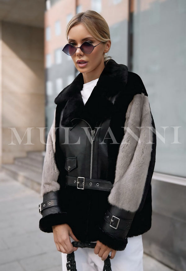 A woman wearing a sleek leather jacket enhanced with soft grey mink fur accents. The jacket combines a modern edge with luxurious fur, creating a stylish and sophisticated look for winter.