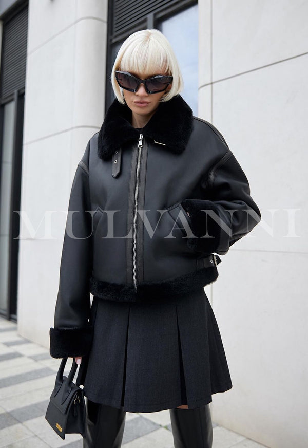 A woman wearing a high-quality black shearling coat paired with stylish sunglasses. The coat features a soft, luxurious texture and a sleek design, offering both warmth and a chic, sophisticated look.