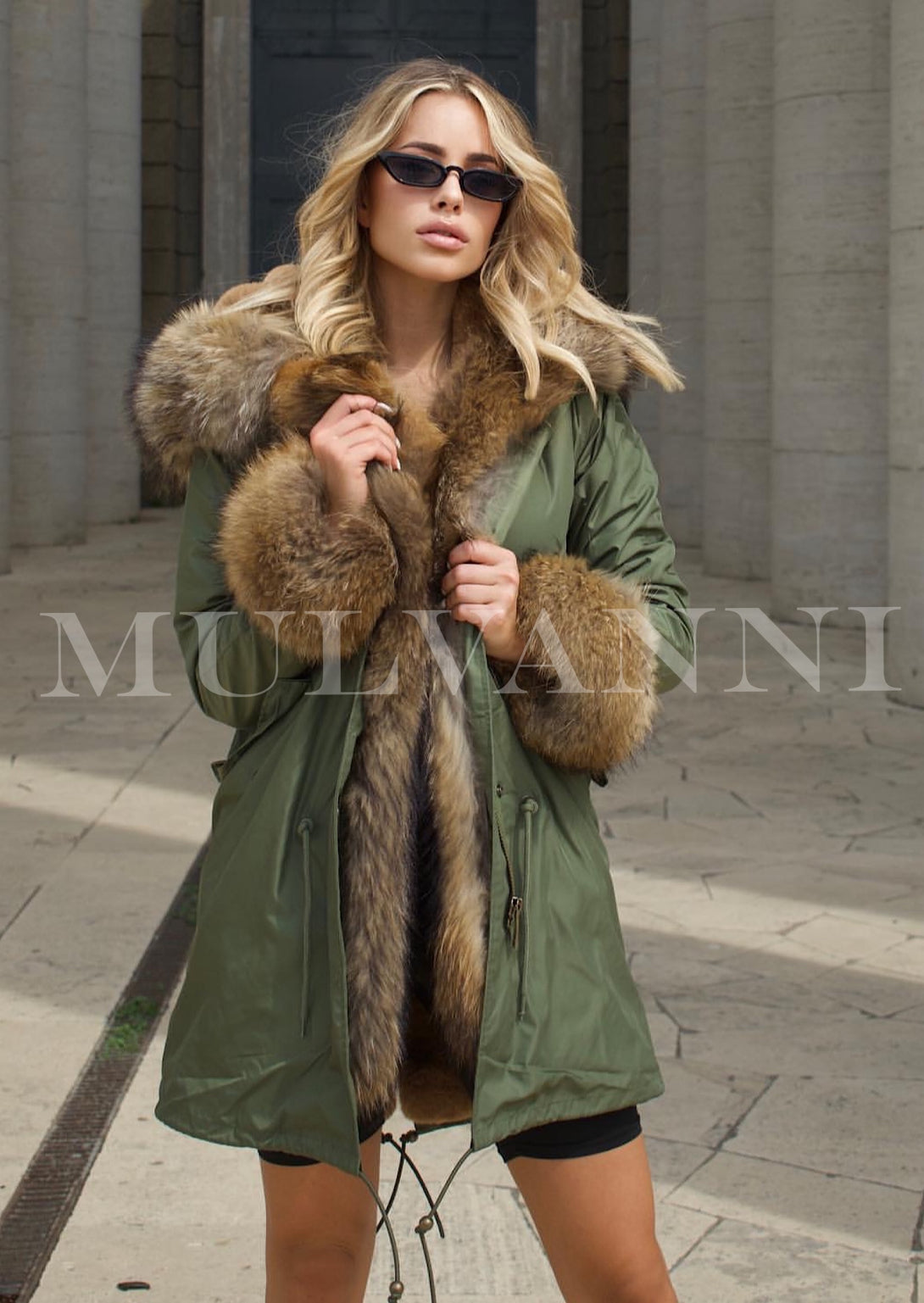 A stylish woman in a green parka featuring plush red fox fur lining. The combination of colors enhances the parka’s elegance while providing comfort and sophistication.