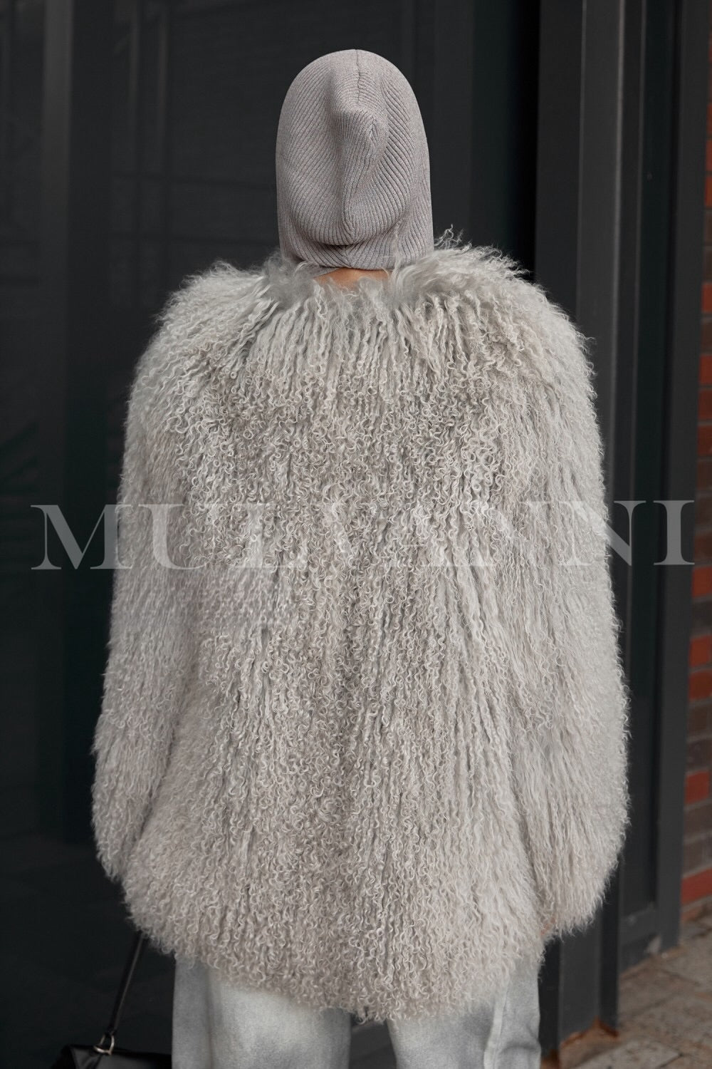 A woman wearing a chic grey Mongolian coat, characterized by its plush texture and sophisticated silhouette. The coat combines comfort and high fashion, making it a standout piece for winter attire.