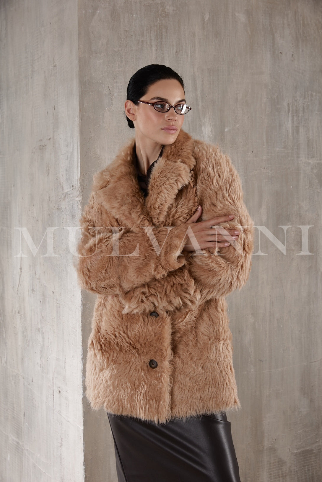 A women's short camel shearling coat with a cozy, plush lining and a boxy silhouette. The coat features wide lapels, a front button closure, and a slightly cropped length for a chic, modern style.