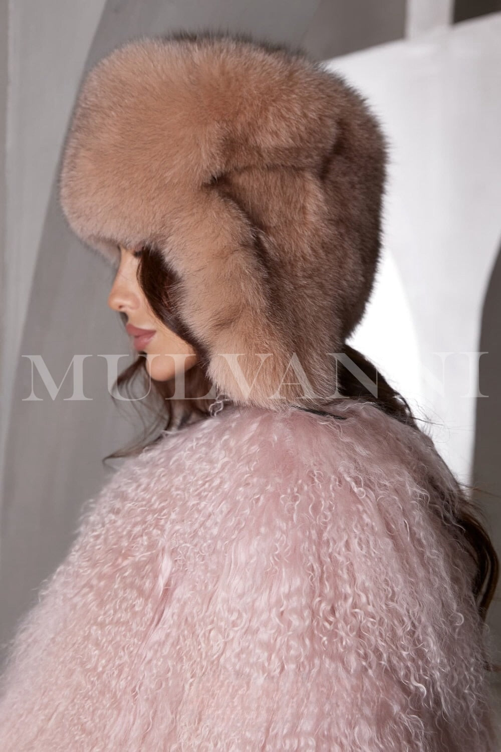 A woman in a chic camel fox fur hat, showcasing a plush, elegant texture and a fitted design. The hat complements her winter attire, providing warmth and sophistication.