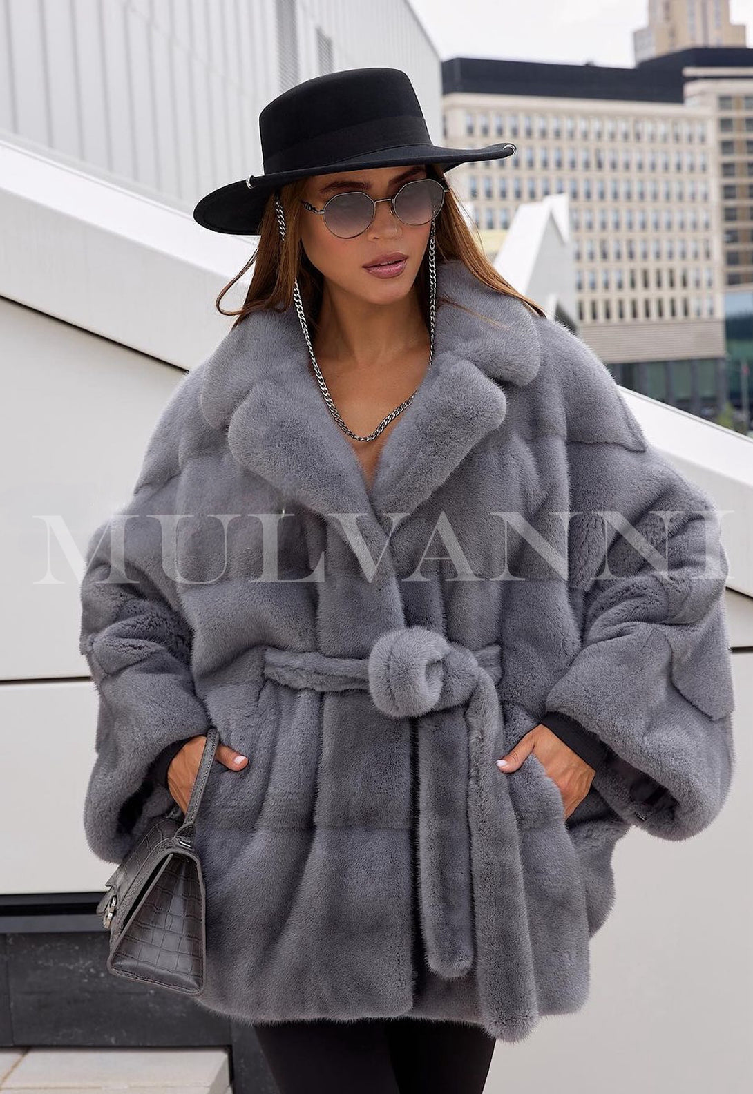 A women's grey mink short coat featuring a soft, luxurious fur texture and a belted waist for a flattering silhouette. The coat has a short length, wide lapels, and a smooth, elegant finish, offering a sophisticated and timeless look.