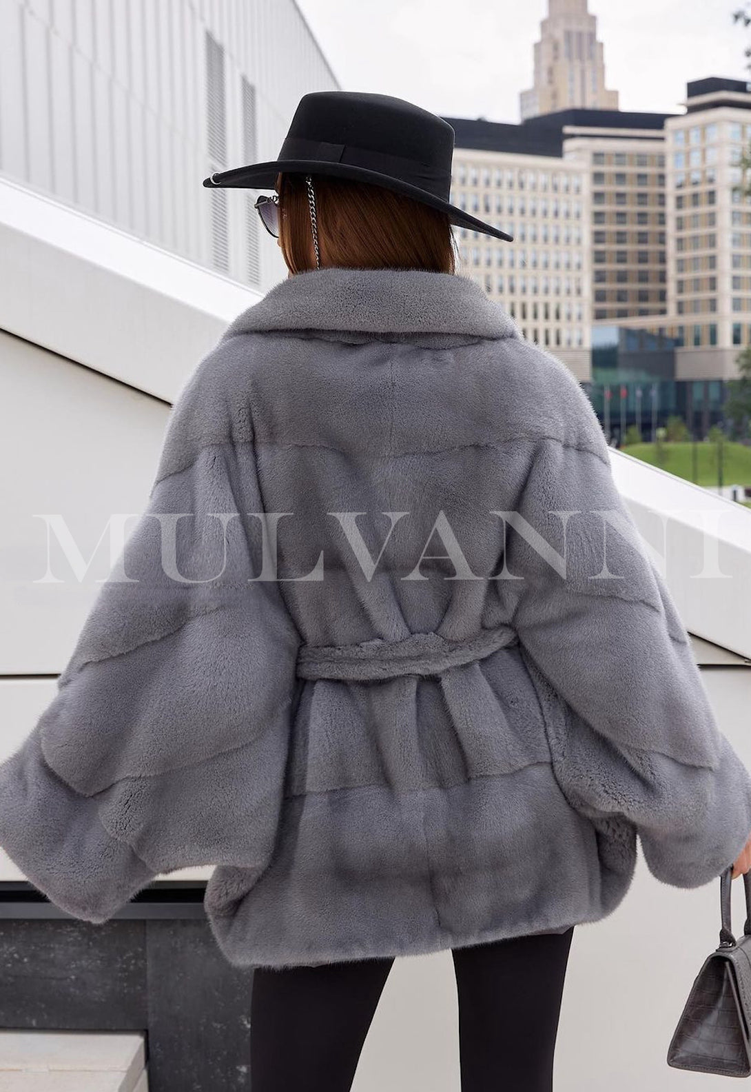 A woman wearing grey mink fur short coat for women, featuring a smooth, lustrous texture and a belt that accentuates the waist. 