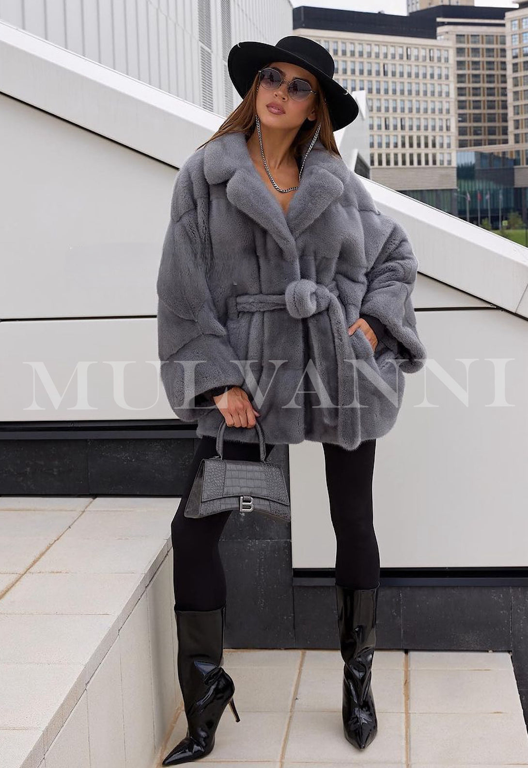 A short grey mink coat for women with a plush fur texture and a matching belt to cinch the waist. The coat features a sleek, cropped design with wide lapels and a rich, glossy finish, exuding elegance and luxury.