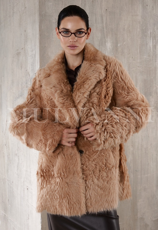  A short camel shearling coat for women, featuring a soft, fluffy lining and a cropped design. The coat has wide lapels, a relaxed fit, and button closures, offering warmth and a casual, stylish look.