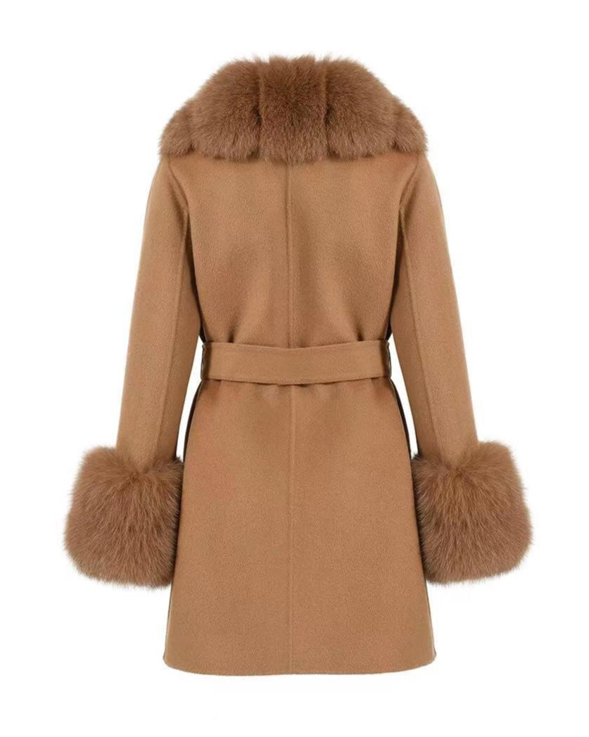 A timeless short camel cashmere coat with soft fox fur detailing and gold buttons, worn by a woman who exudes elegance and understated luxury.